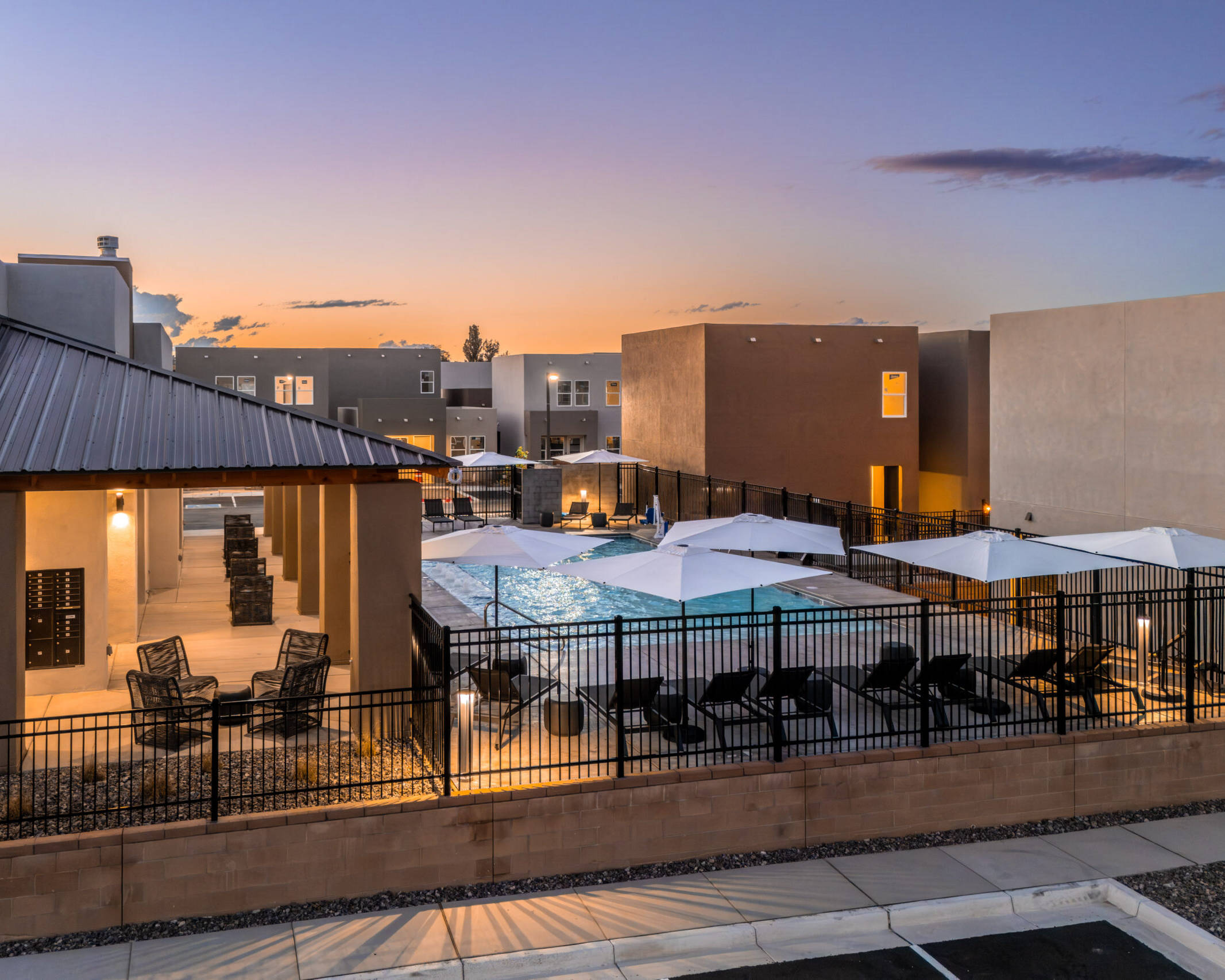 overlooking in-ground pool and lounge chairs with white umbrellas at twilight