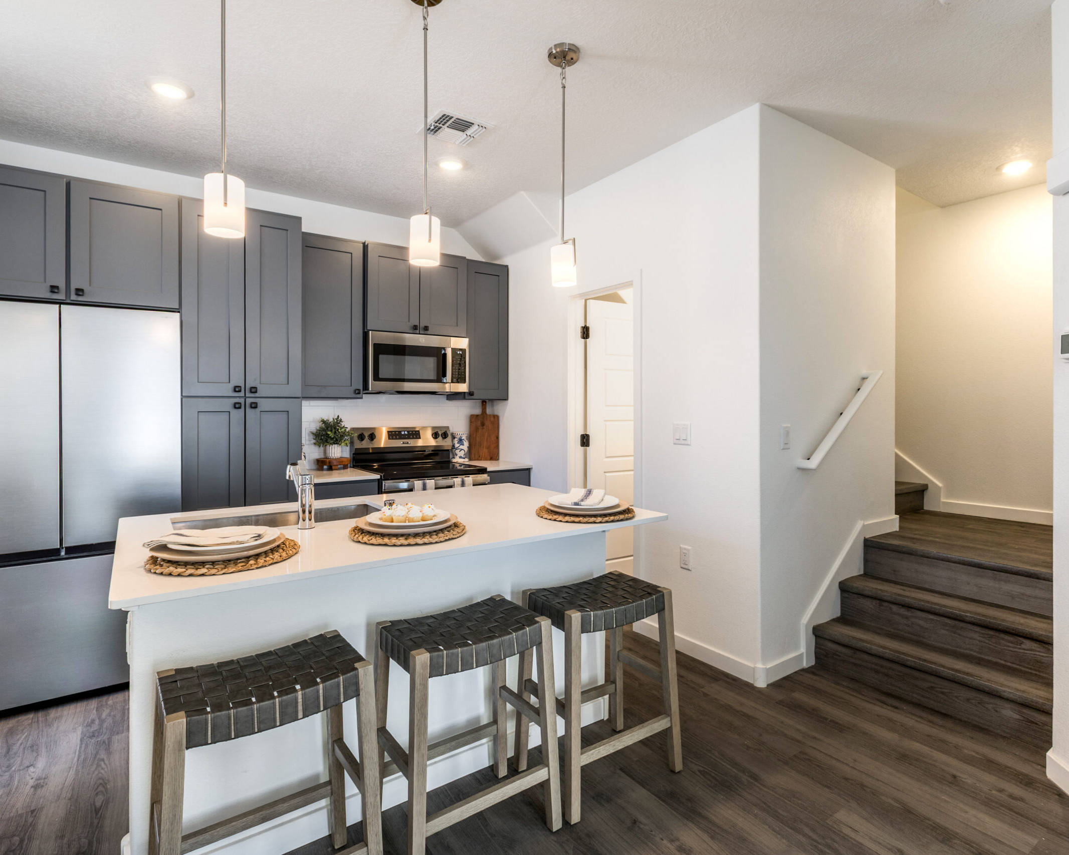 open-style kitchen with barstools, stainless steel appliances, and stairs leading up to the right
