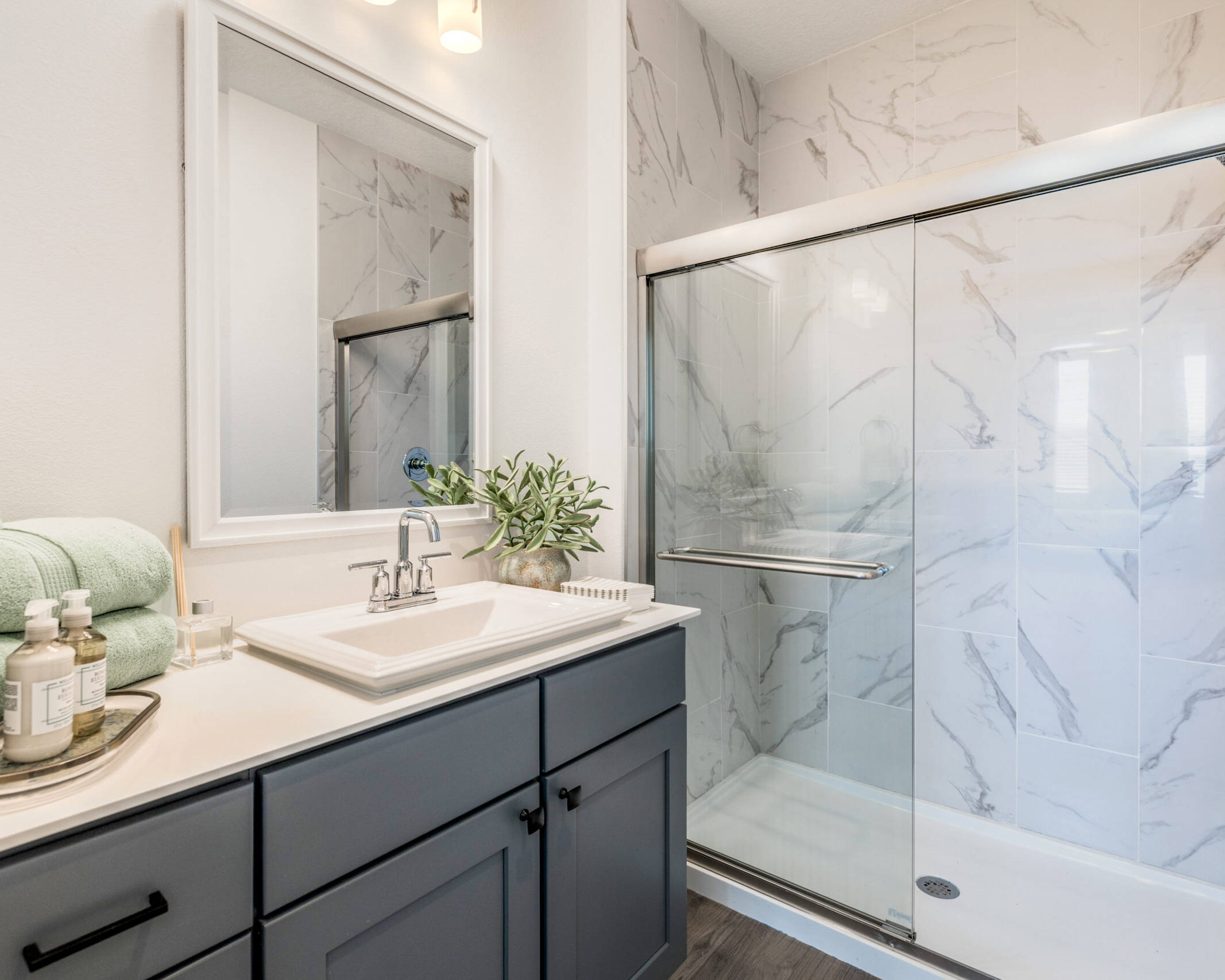 modern bathroom with marble shower walls, glass slding shower doors, and sleek vanity.